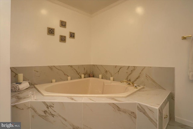 bathroom featuring baseboards, ornamental molding, and a garden tub