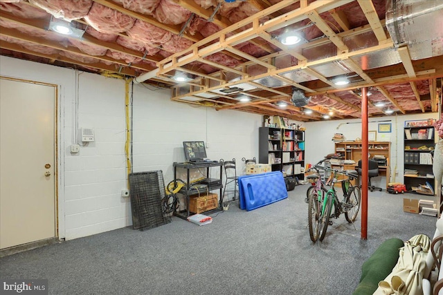 unfinished basement featuring concrete block wall and carpet