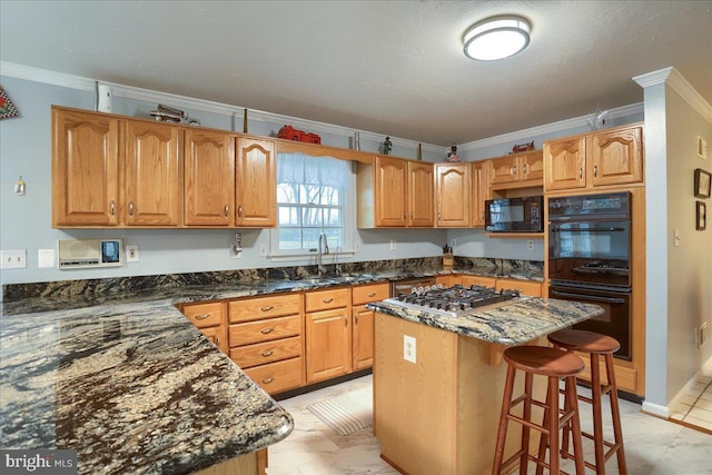 kitchen with a kitchen bar, crown molding, a sink, black appliances, and dark stone countertops