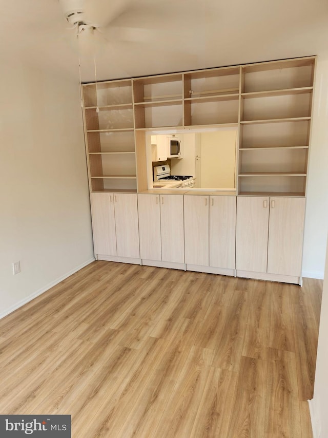 unfurnished dining area featuring light wood-type flooring and baseboards
