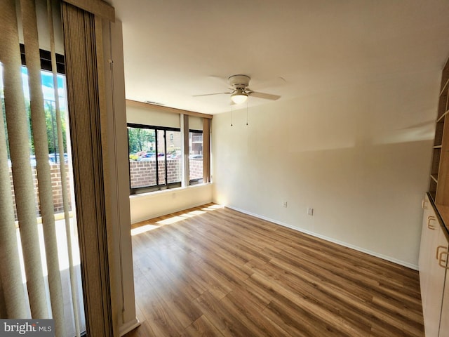 unfurnished room featuring a ceiling fan, wood finished floors, and baseboards