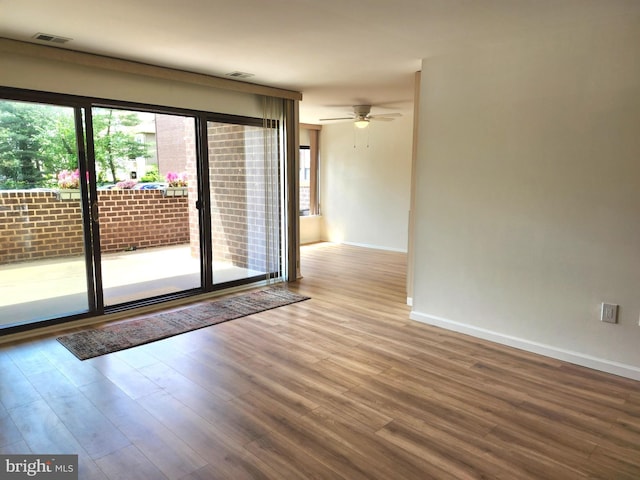 empty room with wood finished floors, baseboards, and ceiling fan