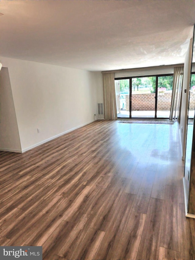 unfurnished room with dark wood-style floors and baseboards