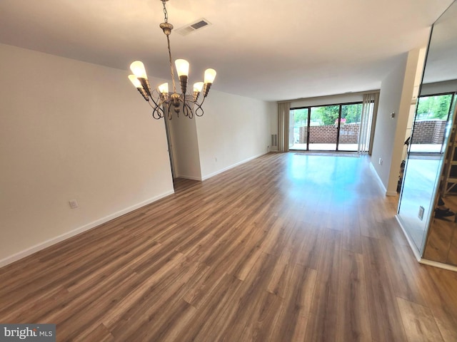 unfurnished room with a chandelier, dark wood finished floors, and baseboards