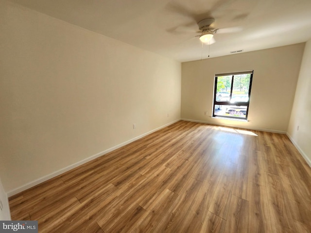 spare room featuring wood finished floors, ceiling fan, and baseboards