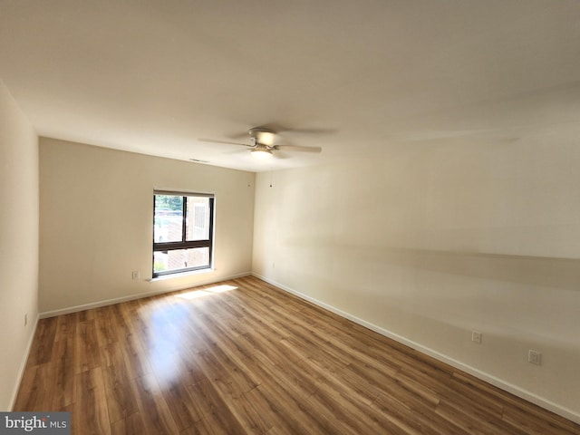 spare room featuring wood finished floors, ceiling fan, and baseboards