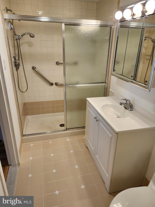 bathroom featuring a shower stall, tile patterned floors, vanity, and toilet