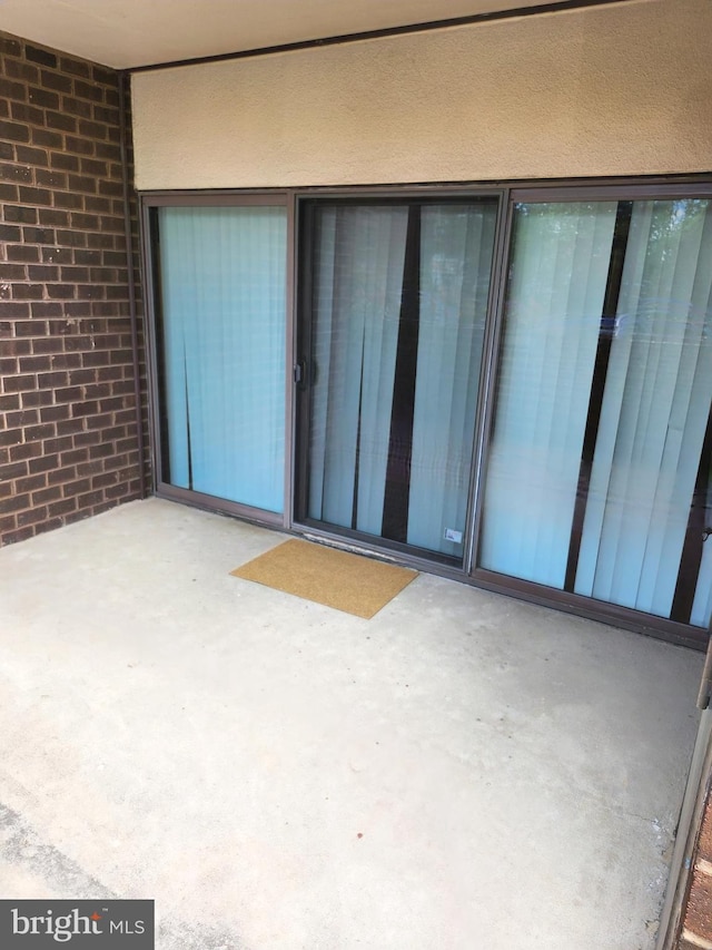 doorway to property featuring a patio area and brick siding