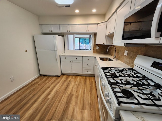 kitchen featuring white appliances, a sink, light wood-type flooring, light countertops, and baseboards