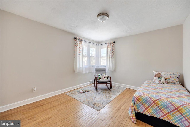 bedroom featuring a textured ceiling, baseboards, and wood finished floors