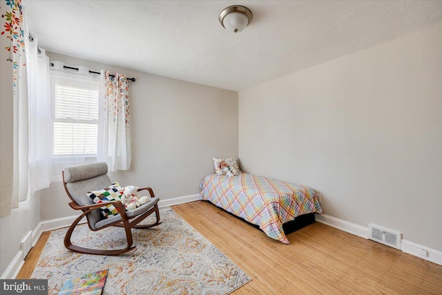 bedroom featuring a textured ceiling, wood finished floors, visible vents, and baseboards