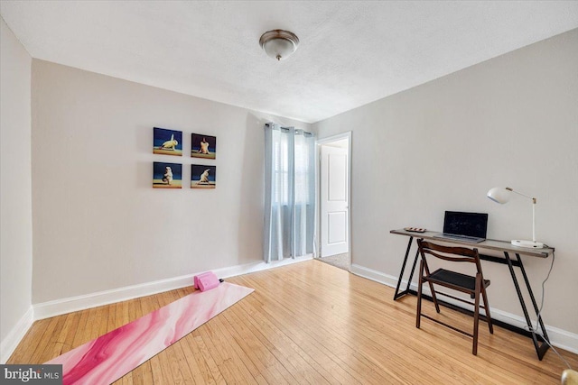 office area with a textured ceiling, wood finished floors, and baseboards