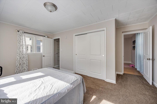 bedroom featuring carpet floors, a closet, crown molding, and baseboards