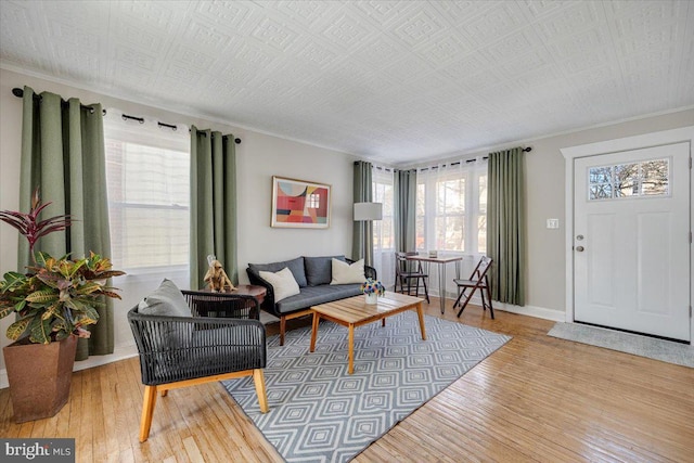 living room with ornamental molding, baseboards, and light wood finished floors