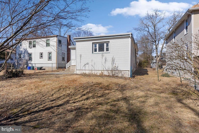 rear view of house featuring a yard and fence