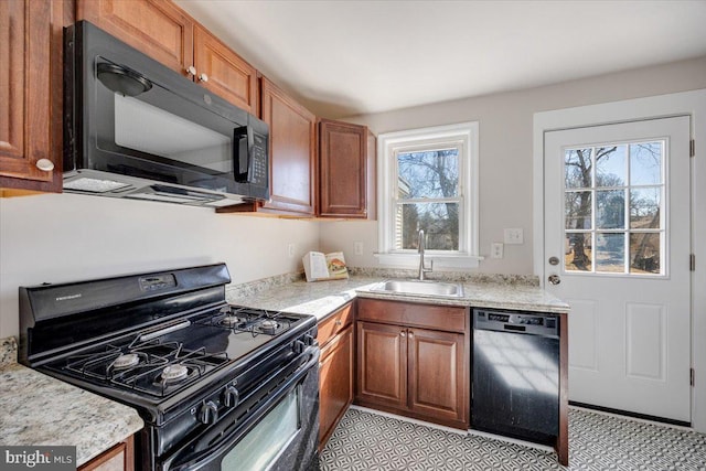 kitchen featuring black appliances, brown cabinetry, a sink, and a wealth of natural light