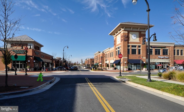 view of road featuring street lights, sidewalks, curbs, a residential view, and traffic signs