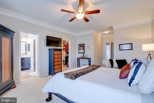 bedroom featuring a walk in closet, ensuite bathroom, ornamental molding, light carpet, and baseboards