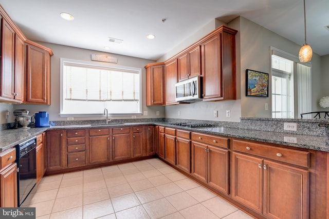 kitchen with recessed lighting, appliances with stainless steel finishes, brown cabinetry, a sink, and dark stone counters