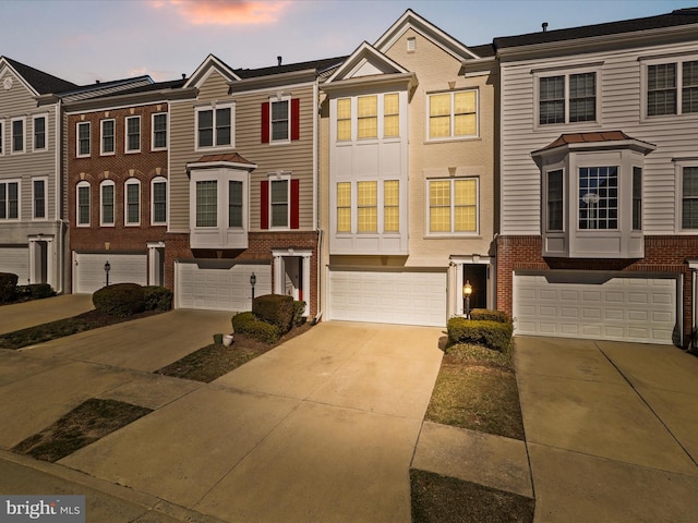 multi unit property with driveway, an attached garage, and brick siding