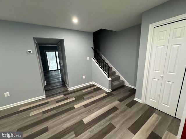 interior space featuring dark wood-style flooring, stairway, and baseboards