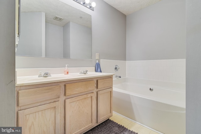 full bathroom with a bath, double vanity, a textured ceiling, and a sink