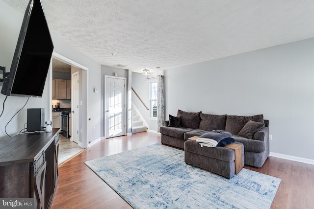 living area featuring a textured ceiling, visible vents, baseboards, stairs, and dark wood-style floors