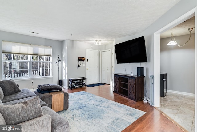 living room with a textured ceiling, wood finished floors, and baseboards