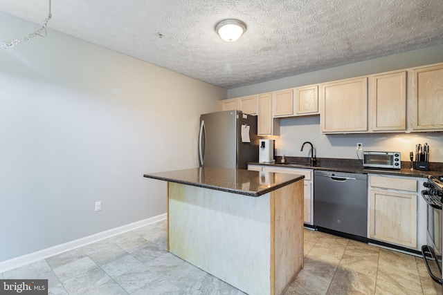 kitchen featuring a toaster, a kitchen island, appliances with stainless steel finishes, dark stone countertops, and a sink