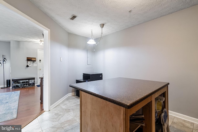 kitchen featuring a textured ceiling, dark countertops, and a kitchen island