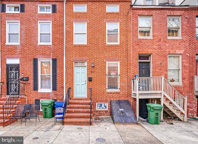 view of property featuring entry steps, brick siding, and a patio