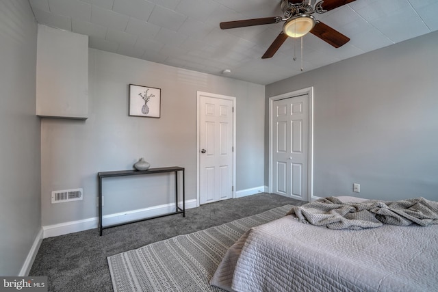 bedroom with baseboards, visible vents, dark colored carpet, and a closet