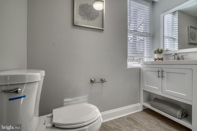 bathroom with vanity, wood finished floors, toilet, and baseboards