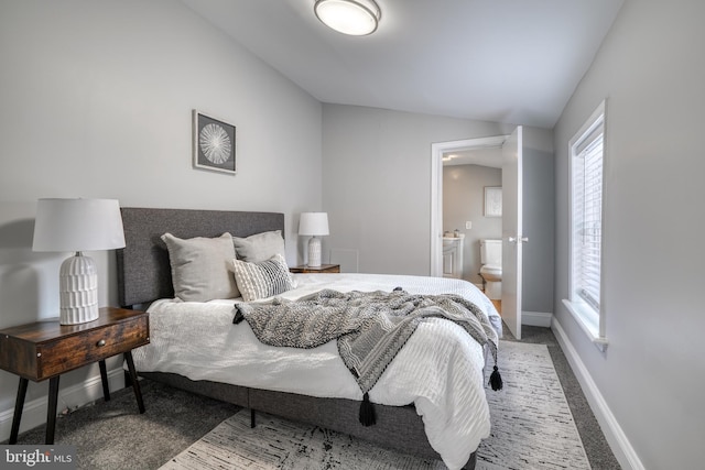 carpeted bedroom featuring lofted ceiling, connected bathroom, and baseboards