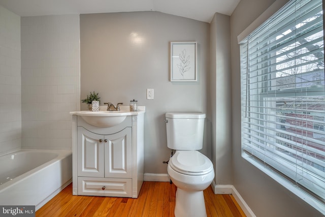 full bath featuring baseboards, vanity, a bathing tub, and wood finished floors