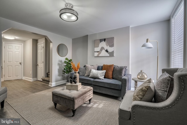 living room with arched walkways, wood finished floors, and baseboards