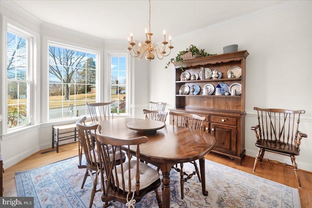 dining area featuring ornamental molding, light wood finished floors, a chandelier, and baseboards