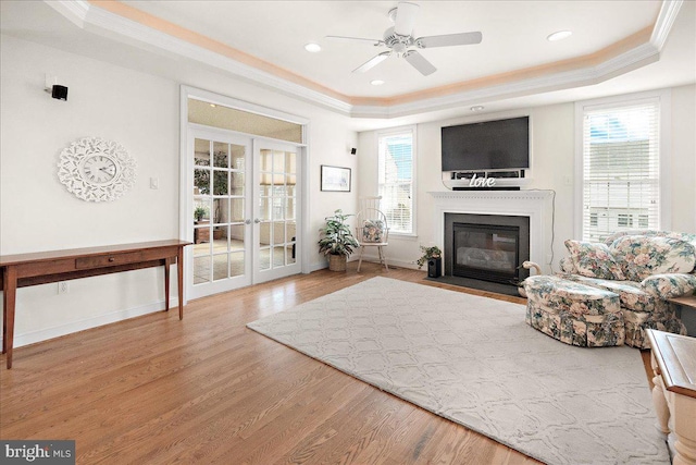 interior space with ornamental molding, a raised ceiling, a fireplace with flush hearth, and wood finished floors