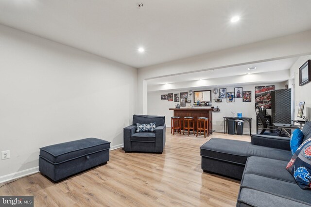 living area featuring light wood finished floors, recessed lighting, bar, and baseboards