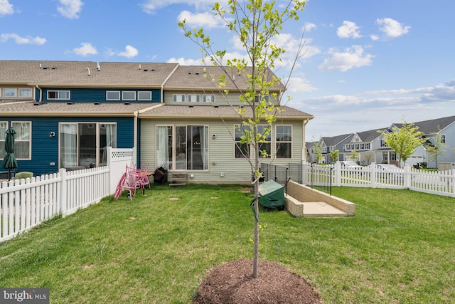 back of property featuring roof with shingles, a fenced backyard, a residential view, and a lawn