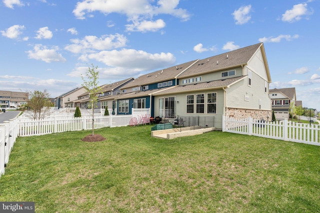 back of property with a fenced backyard, a residential view, a yard, and a patio area