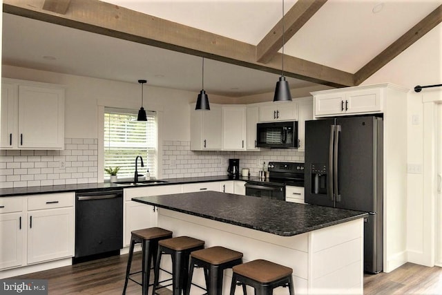 kitchen featuring dark countertops, black appliances, white cabinets, and a center island