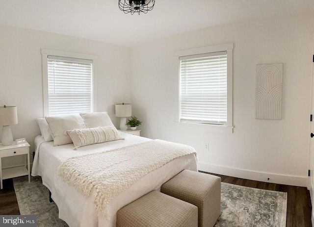 bedroom with baseboards and dark wood-type flooring