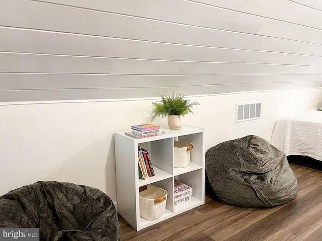 sitting room with visible vents, vaulted ceiling, and wood finished floors