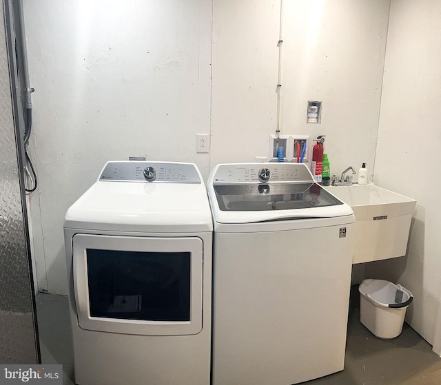 washroom with laundry area, a sink, and independent washer and dryer