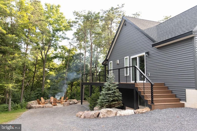 view of side of property with a patio area, an outdoor fire pit, stairway, and a shingled roof