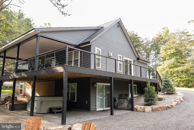 view of front of house featuring a hot tub, a wooden deck, and a patio