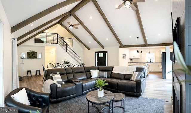 living room with stairs, high vaulted ceiling, beamed ceiling, and wood finished floors