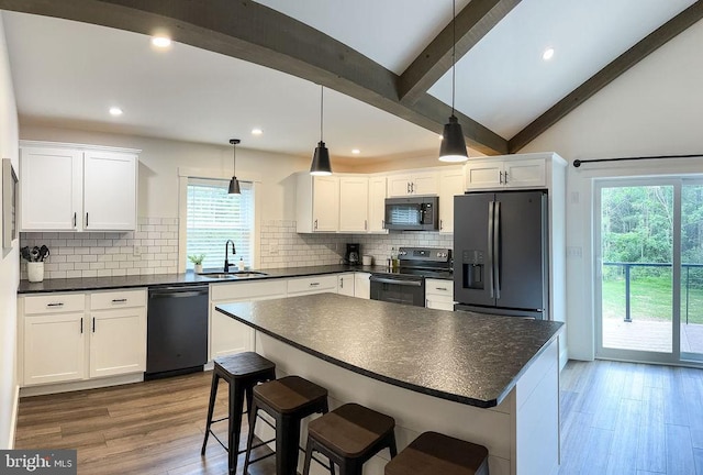 kitchen featuring dark countertops, white cabinets, a sink, and black appliances