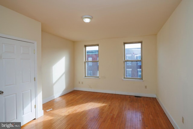 spare room featuring light wood-type flooring and baseboards